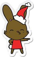 dessin animé autocollant lapin curieux d'un bonnet de noel portant vecteur