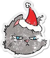 dessin animé autocollant en détresse d'un visage de chat dur portant un bonnet de noel vecteur