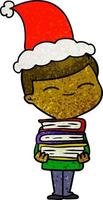 dessin animé texturé d'un garçon souriant avec une pile de livres portant un bonnet de noel vecteur