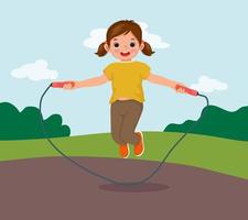 heureuse petite fille sautant la corde à sauter au parc vecteur