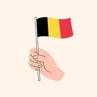 main de dessin animé tenant l'icône du drapeau belge. le drapeau de la belgique, illustration du concept. vecteur isolé de conception plate.