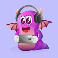 mignon monstre violet jouant au jeu mobile, portant des écouteurs vecteur