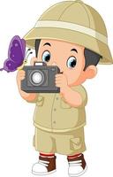 une mignonne aventureux garçon est observer une papillon et porter une caméra vecteur