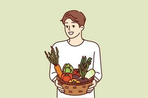 homme avec panier de des légumes sourit et recommande Aller végétalien ou en mangeant biologique brut aliments. végétarien gars des offres à acheter ferme des légumes et début Nouveau en bonne santé régime à améliorer santé vecteur