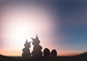 Silhouette de lapins de Pâques contre un ciel coucher de soleil vecteur
