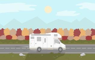 un camping-car ou une caravane roule sur une autoroute sur fond d'automne.