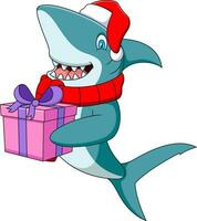 mignonne dessin animé requin dans une Père Noël chapeau est en portant une cadeau boîte vecteur
