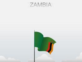 le drapeau de la zambie flotte sur un poteau qui se dresse sous le ciel blanc vecteur