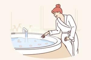 femme des stands près chaud baignoire rempli avec fleur pétales, avoir prêt pour aromatique spa traitement avec rajeunissant effet. content fille dans peignoir de bain visites spa salon avec mini bassin de l'eau vecteur