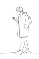 Jeune homme dans une manteau ou parka avec une sac à dos des promenades vers le bas le rue à la recherche à le sien téléphone. un ligne dessin portant vêtements d'extérieur vecteur