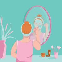 jeune femme applique un masque facial avec une brosse devant le miroir vecteur