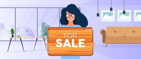 une femme avec des lunettes tient une pancarte en bois avec l'inscription à vendre. jeune femme tenant une pancarte en bois. le concept de vente d'un appartement, d'un bureau ou d'un immeuble. vecteur. vecteur