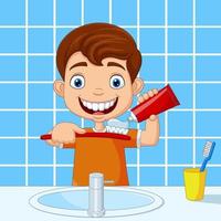 mignon petit garçon se brosser les dents dans la salle de bain vecteur