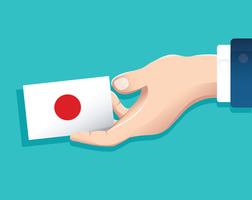 main tenant la carte du drapeau du Japon avec fond bleu vecteur