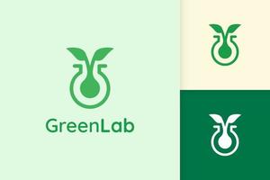 logo de laboratoire vert avec forme de feuille pour la science ou la chimie vecteur