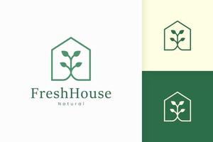 logo de maison verte nature avec forme d'arbre et de feuille vecteur