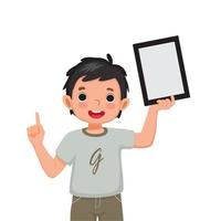 joyeux petit garçon tenant une tablette numérique avec le doigt pointant vers l'espace vide ou l'espace de copie pour les textes, les messages et le contenu publicitaire. enfants et concept de gadgets électroniques pour enfants vecteur