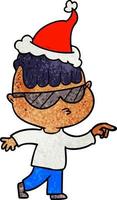 dessin animé texturé d'un garçon portant des lunettes de soleil pointant portant un bonnet de noel vecteur
