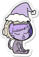 dessin animé autocollant d'une jolie fille astronaute assise en attente portant un bonnet de noel vecteur