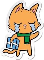 autocollant d'un chat de dessin animé qui pleure tenant un cadeau de noël vecteur