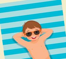vue de dessus d'un mignon petit garçon avec maillot de bain et lunettes de soleil allongé sur une serviette de plage s'amusant à bronzer pendant les vacances d'été vecteur