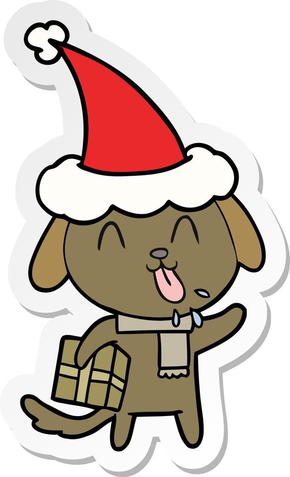 desenho de adesivo fofo de um cachorro com presente de natal usando chapéu de papai noel vetor