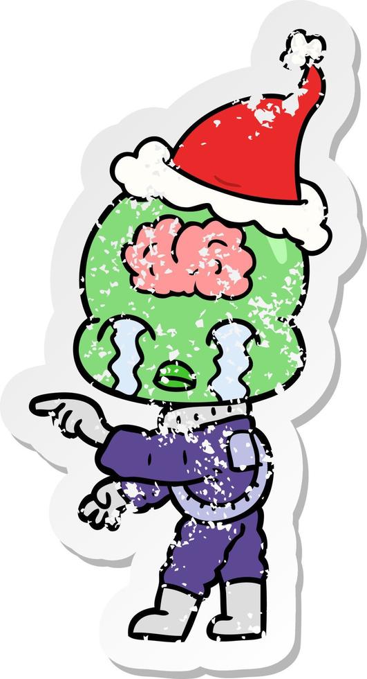 desenho de adesivo angustiado de um alienígena de cérebro grande chorando e apontando usando chapéu de papai noel vetor