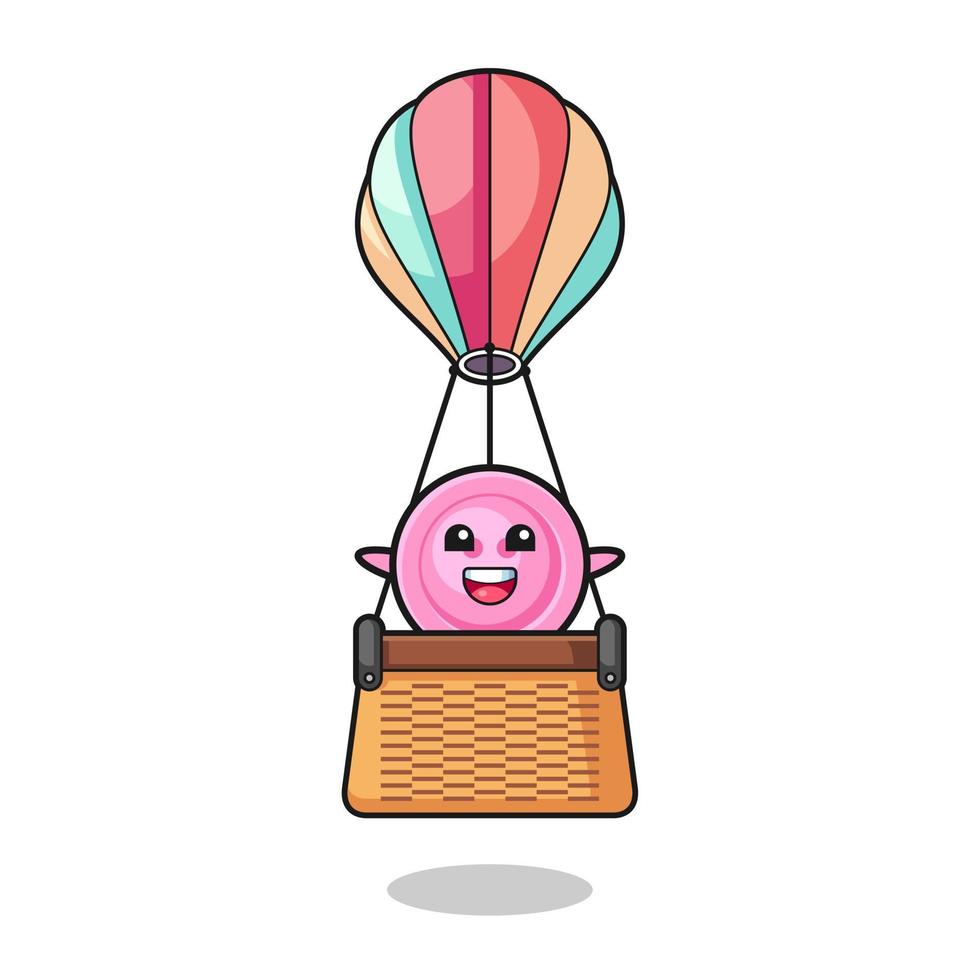 mascote de botão de roupa montando um balão de ar quente vetor