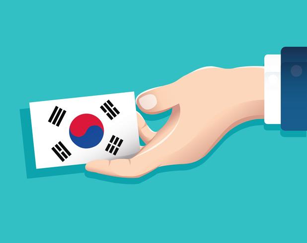 mão segurando o cartão de bandeira da Coreia do Sul com fundo azul vetor