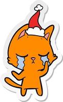 desenho de adesivo chorando de um gato usando chapéu de papai noel vetor