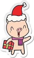 desenho de adesivo feliz de um porco com presente de natal usando chapéu de papai noel vetor