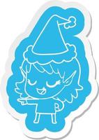 adesivo de desenho animado feliz de uma garota elfa apontando usando chapéu de papai noel vetor
