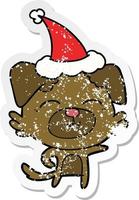 desenho de adesivo angustiado de um cachorro apontando usando chapéu de papai noel vetor