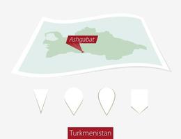 curvado papel mapa do Turquemenistão com capital Ashgabat em cinzento fundo. quatro diferente mapa PIN definir. vetor