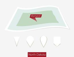 curvado papel mapa do norte Dakota Estado com capital bismarck em cinzento fundo. quatro diferente mapa PIN definir.