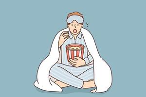 homem dentro pijama debaixo cobertor comer Pipoca Assistir filme às lar. surpreso cara vestem pijama apreciar filme noite dentro de casa com lanches. vetor ilustração.