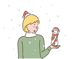 uma garota está olhando com um pequeno boneco de neve nas mãos. ambos estão usando chapéus de Papai Noel. mão desenhada estilo ilustrações vetoriais. vetor
