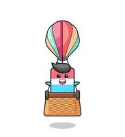 mascote da borracha montando um balão de ar quente vetor