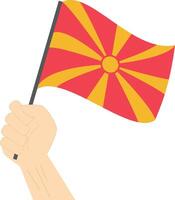 mão segurando e levantando a nacional bandeira do Macedônia vetor