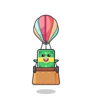 mascote de dinheiro montando um balão de ar quente vetor
