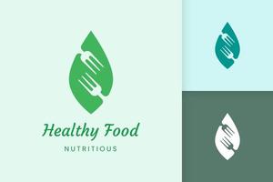 logotipo de comida saudável com forma de garfo e folha vetor