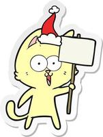 desenho de adesivo engraçado de um gato com placa usando chapéu de papai noel vetor
