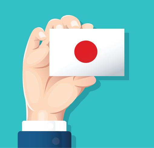 mano che tiene la carta della bandiera del Giappone con sfondo blu vettore