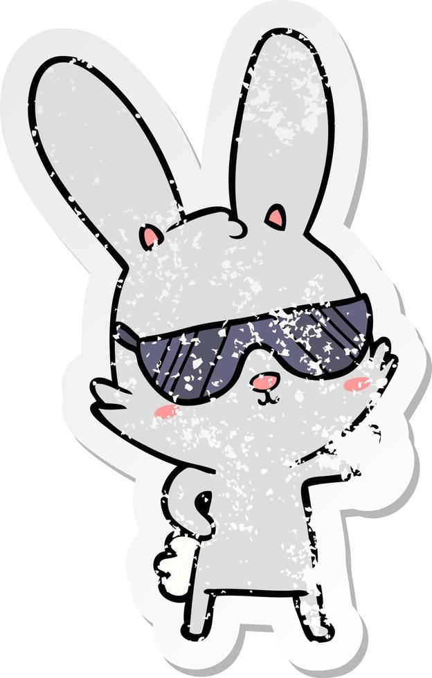 adesivo angosciato di un simpatico coniglio cartone animato che indossa occhiali da sole vettore