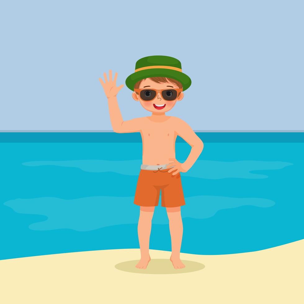 ragazzino carino in costume da bagno con cappello e occhiali da sole divertendosi sulla spiaggia agitando la mano in posa durante le vacanze estive vettore