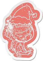 adesivo in difficoltà cartone animato di una bella ragazza astronauta seduta in attesa che indossa il cappello di Babbo Natale vettore