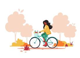 donna nera in sella a bici nel parco in autunno. stile di vita sano, sport, concetto di attività all'aperto. illustrazione vettoriale. vettore