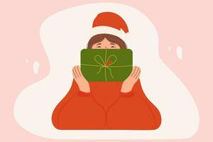 donna nel Santa cappello copertura sua viso con un' nuovo anni regalo. sorridente ragazza nel un' maglione guardare su di un' Natale scatola vettore