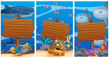 Segni di legno sotto l&#39;oceano con animali marini in background vettore