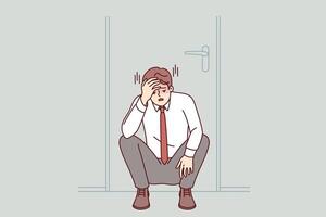 frustrato uomo d'affari si sente impotente quando impara quello fallimento, si siede purtroppo sotto porta nel ufficio vettore